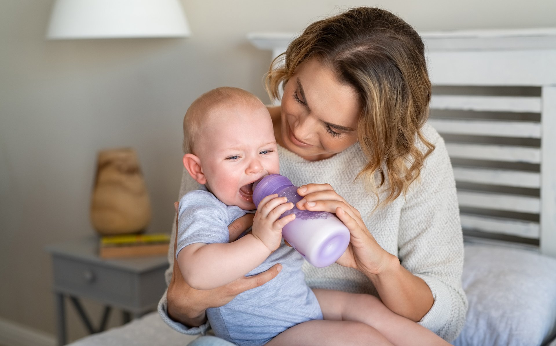 Dziecko gryzie plastikowa butelke z mlekiem
