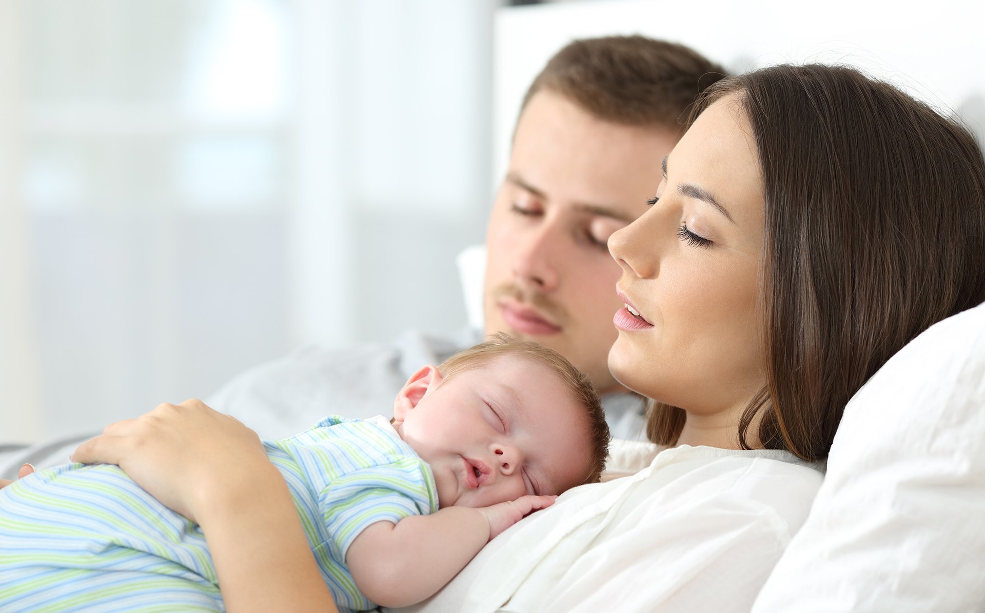 Tata i mama z dzieckiem na brzuchu spia obok siebie