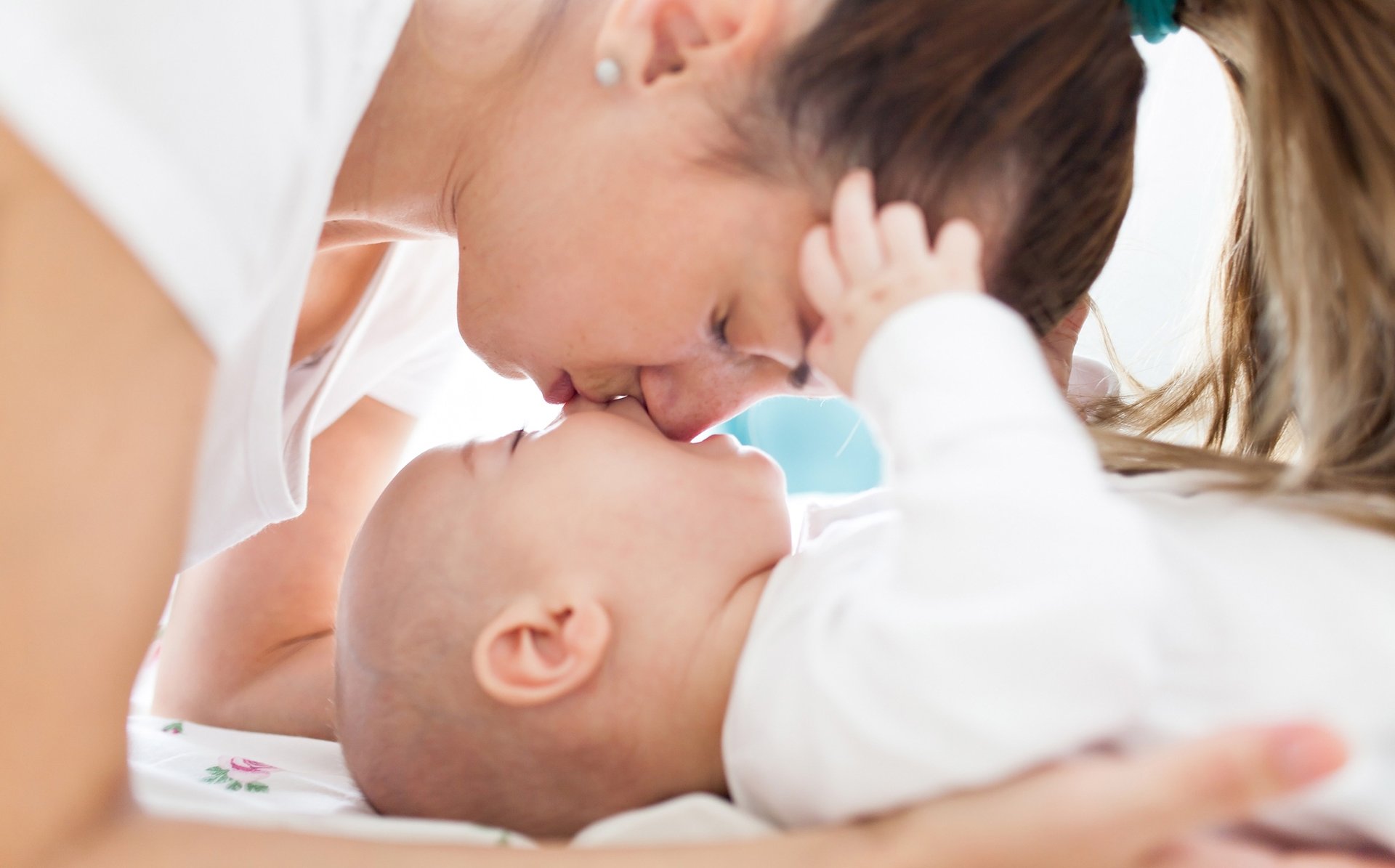 Mama nachyla się nad dzieckiem calujac je w nos