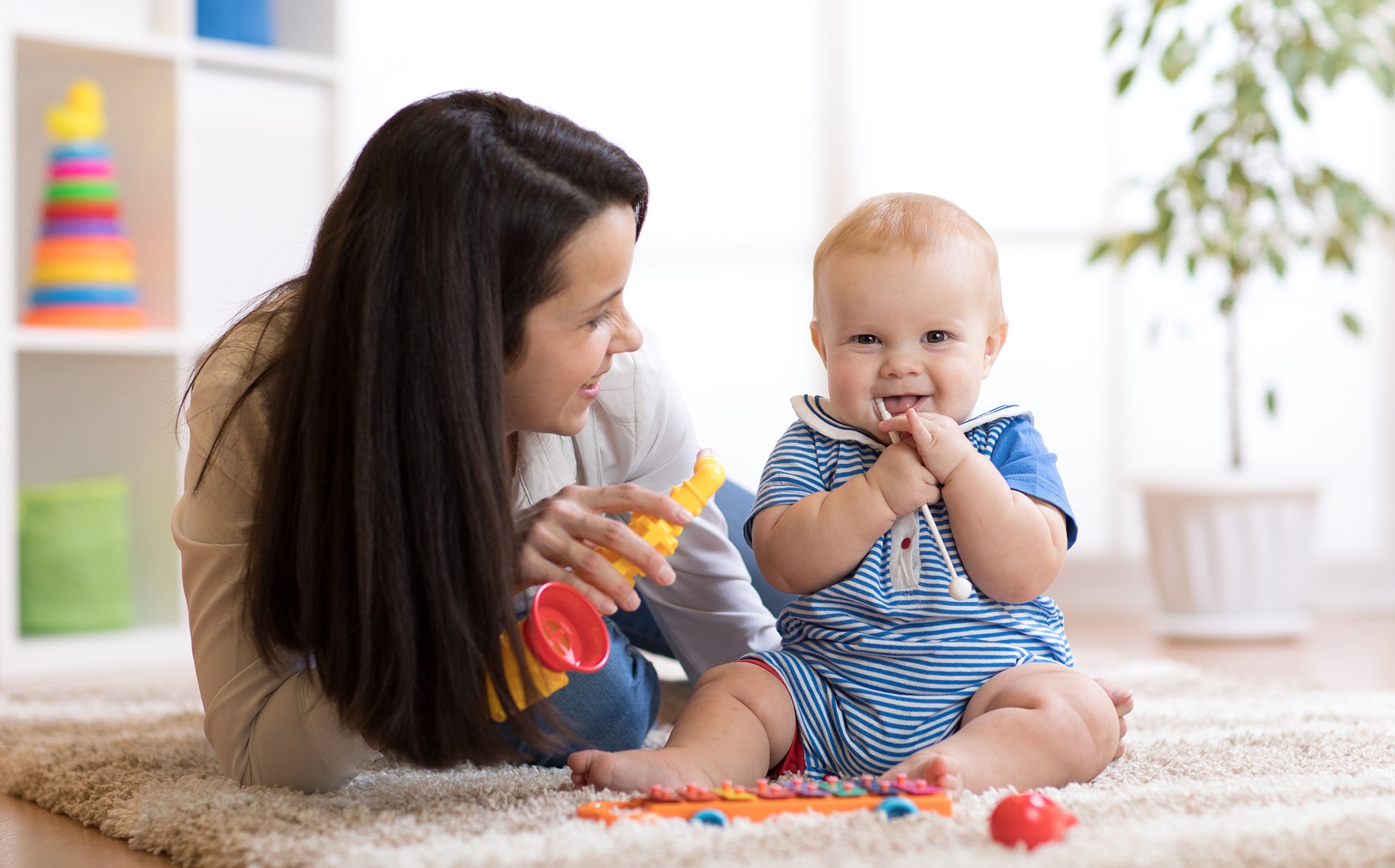 Mama bawi sie z siedzacym dzieckiem na dywanie