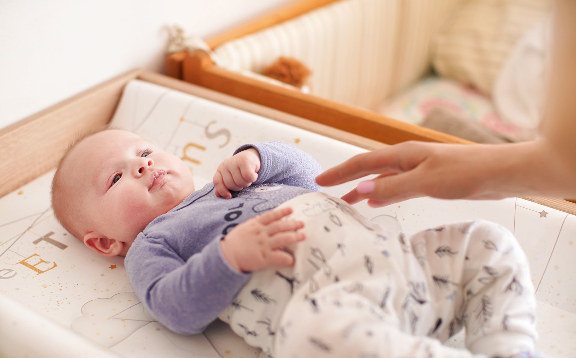 Mama dotyka brzucha dziecka lezacego na przewijaku