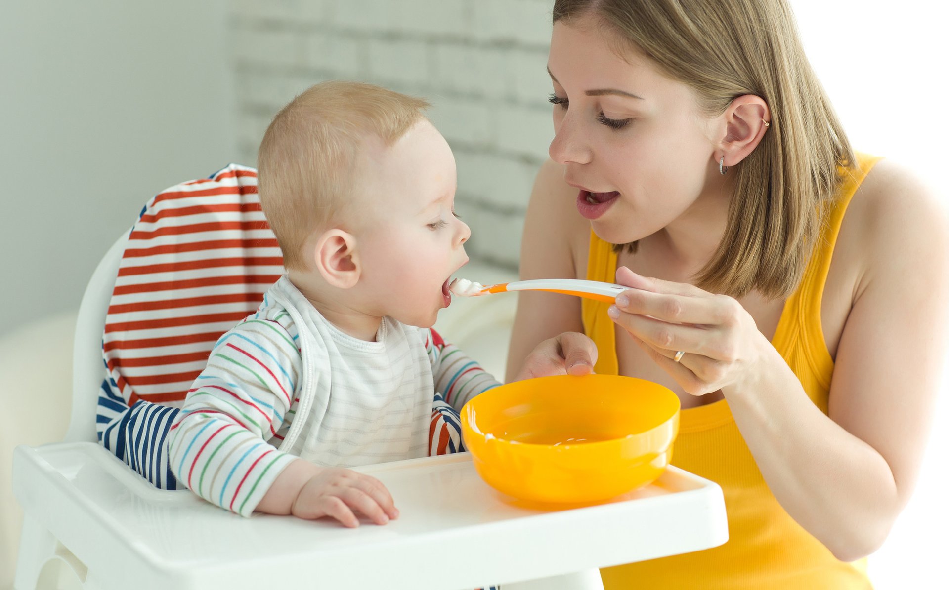 Mama karmi dziecko siedzace na krzesle kaszka