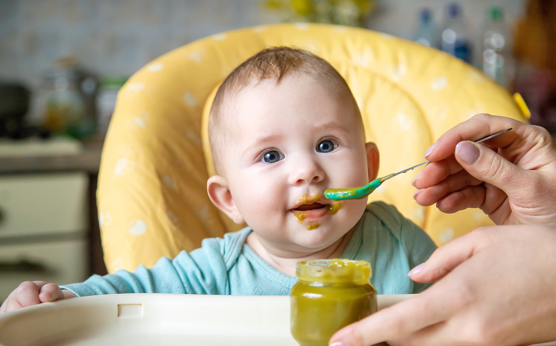 Kobieta karmi dziecko jedzeniem ze sloiczka